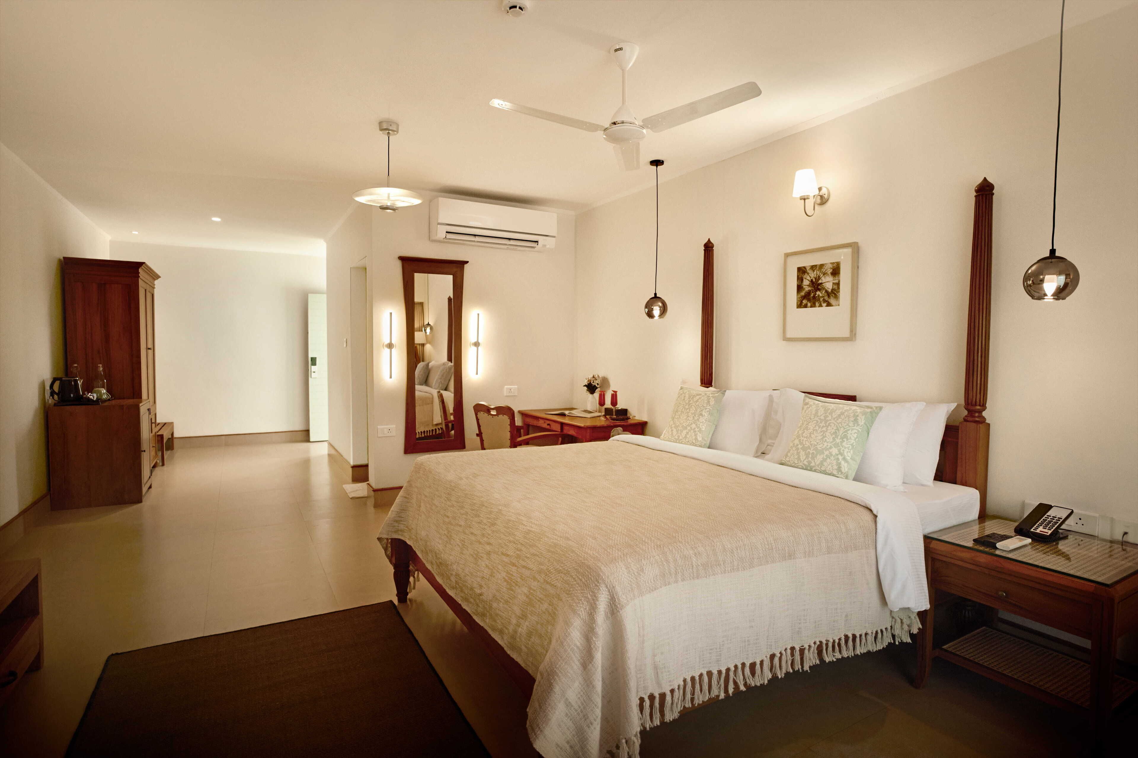 A spacious bedroom with a large bed, bedside tables, a desk, and a wardrobe.