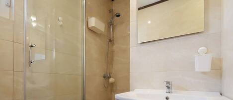 A modern bathroom with a glass shower enclosure, a white sink, and a mirror above the sink.
