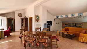 Amplia sala de estar con una mesa de comedor, sillas, un sofá y una cocina al fondo.