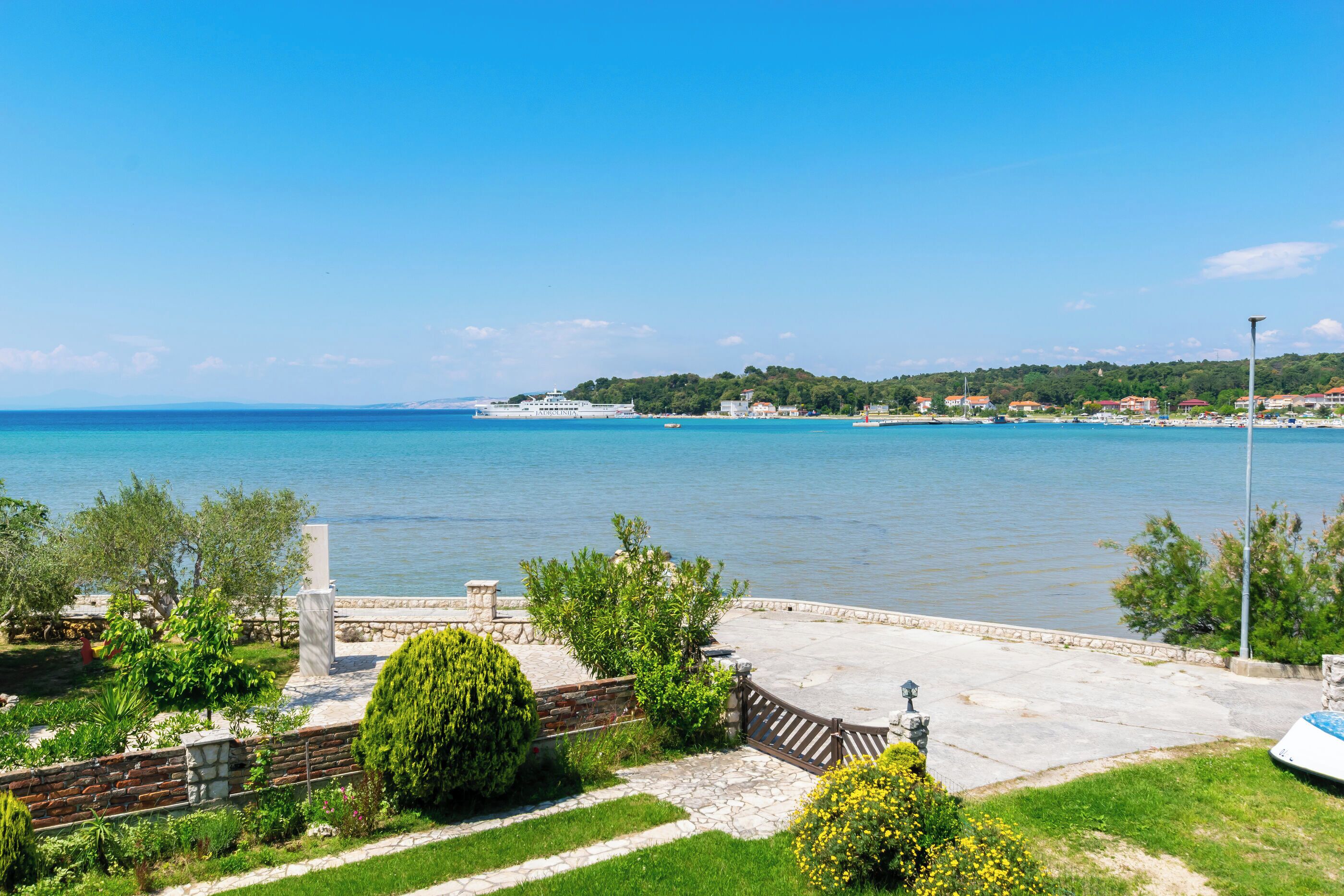 Μια θέα προς την παραλία, με ένα μονοπάτι από πέτρα, ένα παγκάκι και ένα άγαλμα.