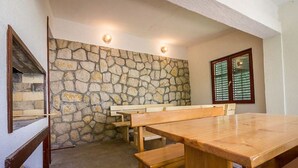 A dining area with a stone wall, wooden benches, and a large table. - Apartment Mario (Lopar)