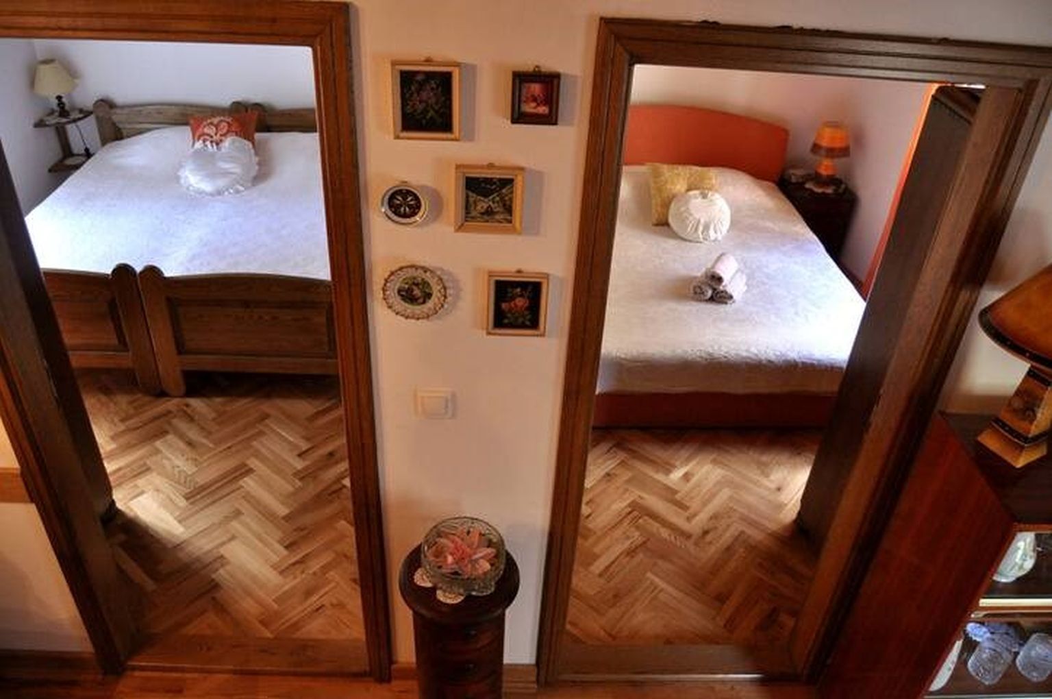 Una stanza con specchi, un letto, un comodino e un tavolino con un vaso.
