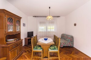 A dining area with a wooden table, chairs, and a cabinet. - Apartments Jerko (Tisno)
