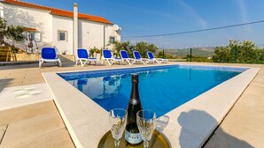 A swimming pool with lounge chairs, a bottle of wine, and glasses on a tray. - House Roko (Marina)