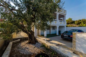 A two-story building with a stone facade, a tree with olives, and a parked car. - House Roko (Marina)