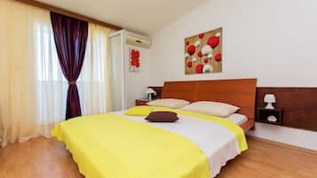 A neatly made bed with a yellow bedspread, a wooden headboard, and a nightstand with a lamp.