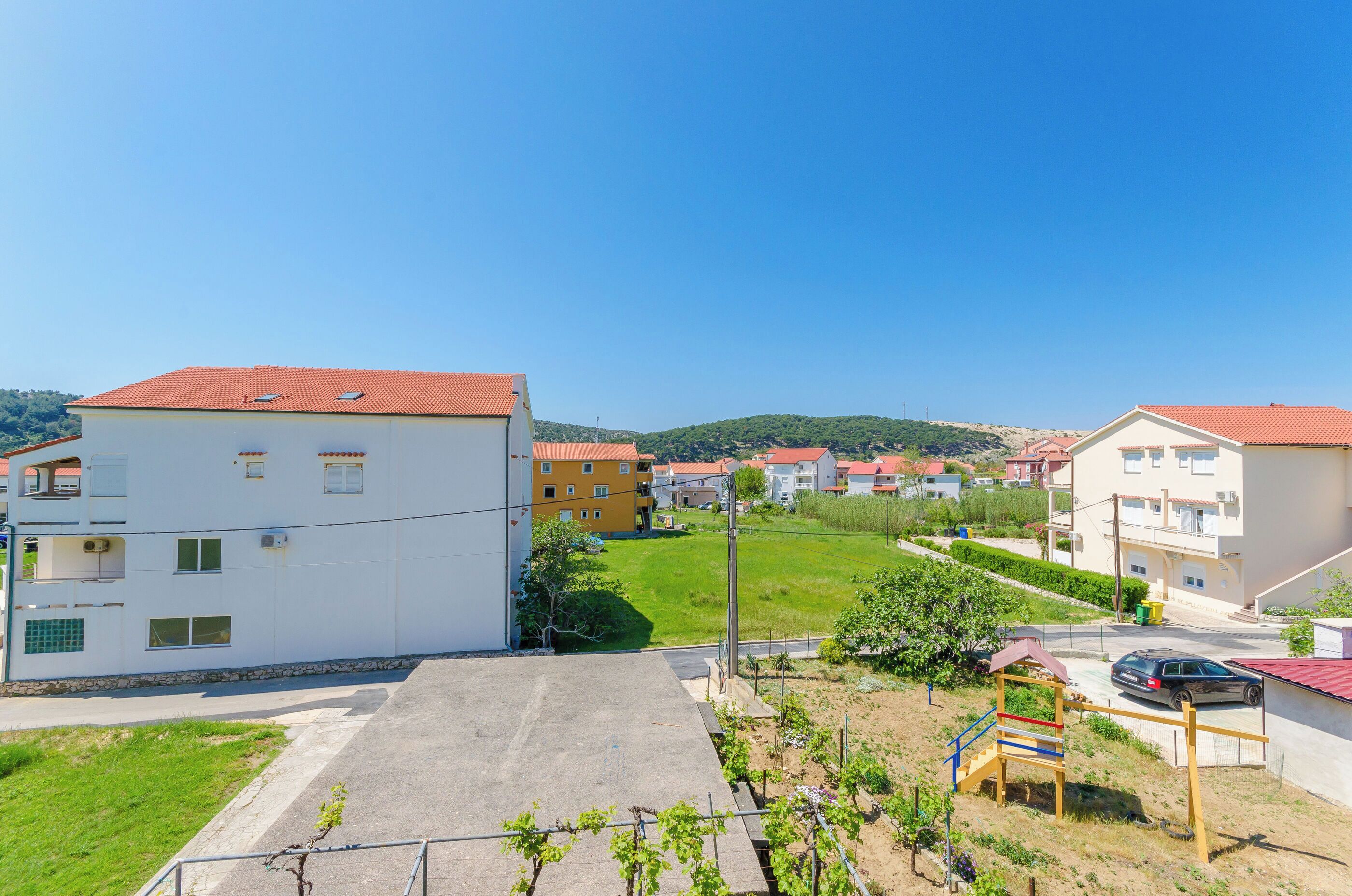 Zona residencial con casas, un parque infantil y cielo despejado.