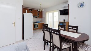 Eine kompakte Küche mit Essbereich, Kühlschrank, Backofen und einem an der Wand montierten Fernseher.
