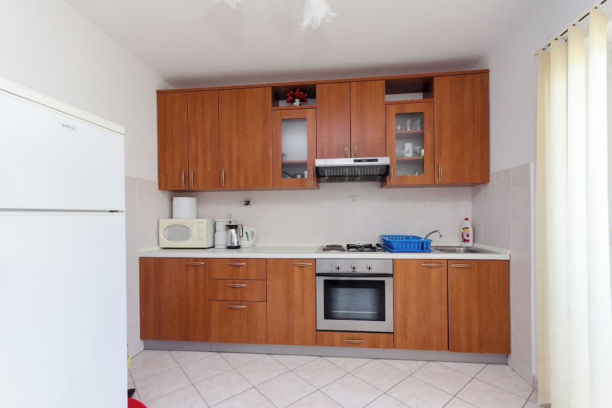 A compact kitchen with wooden cabinets, a built-in microwave, a stove, and a refrigerator.