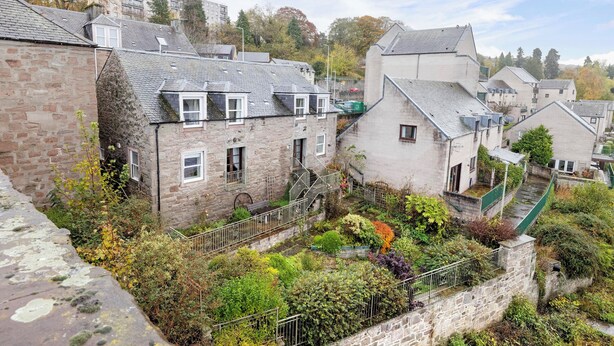 A stone building with a garden in front, a staircase, and a view of other buildings in the background. - Riverside Home in Perth (Perth)