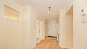 A hallway with wooden flooring, white walls, and a door with glass panels. - Riverside Home in Perth (Perth)