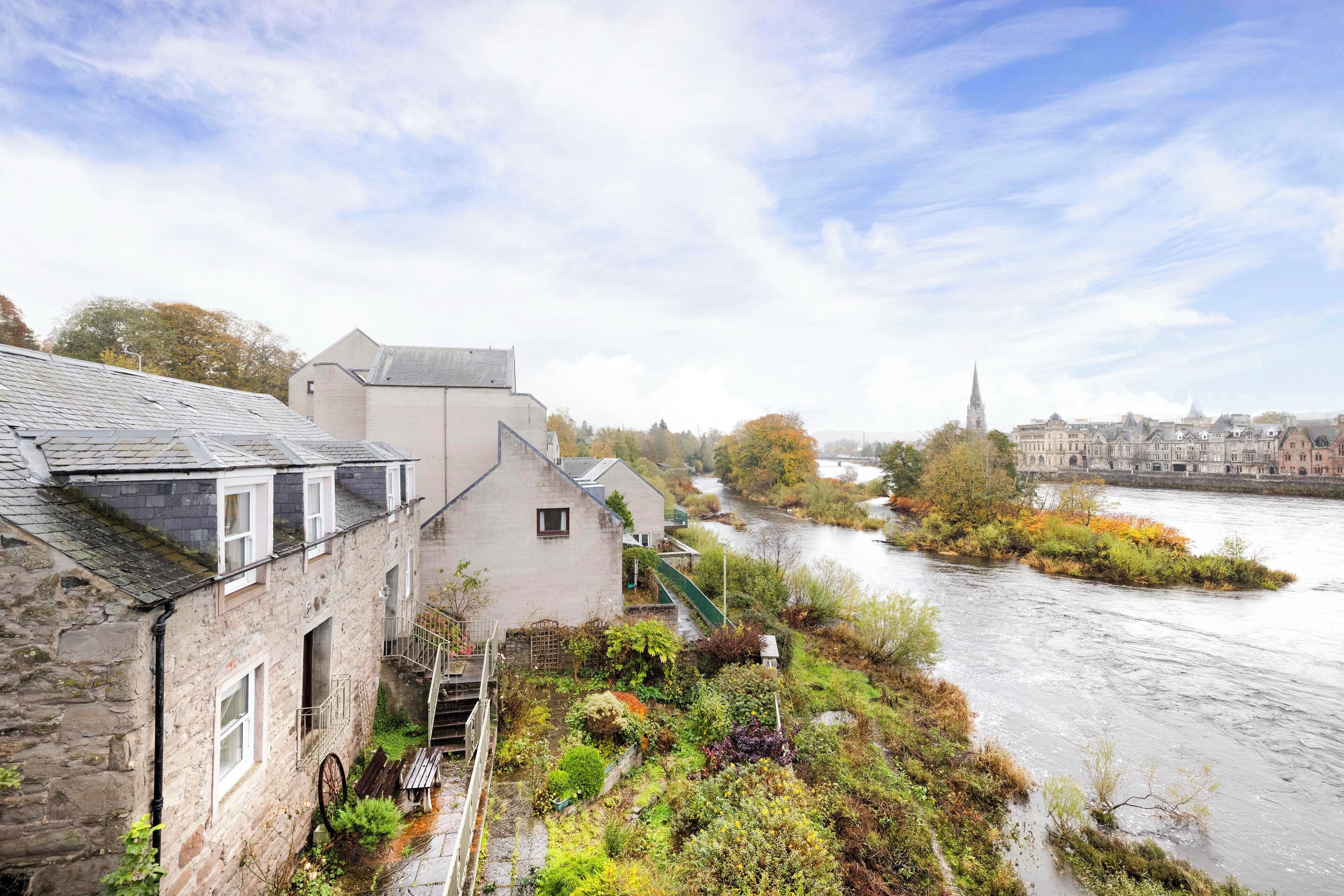 A stone building with a staircase and a river in the background.