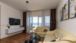 A modern living room with a sofa, a coffee table, a TV, and a balcony with a view. - Apartment Filip (Dugi Rat)