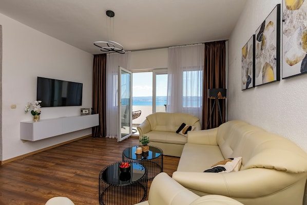 A modern living room with a sofa, a coffee table, a TV, and a balcony with a view. - Apartment Filip (Dugi Rat)