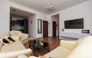 Ein modernes Wohnzimmer mit einer Couch, einem Couchtisch und einem an der Wand befestigten Fernseher.