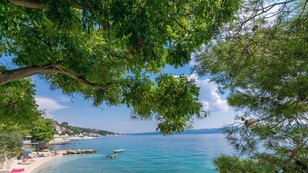 A coastal view with clear water, a beach, and a small boat. - Apartment Filip (Dugi Rat)
