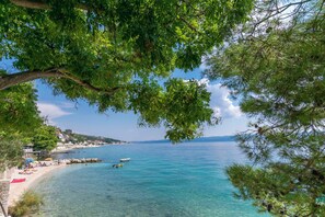 Egy tengerparti kilátás, ahol a víz tiszta, látható egy strand és egy kis csónak.