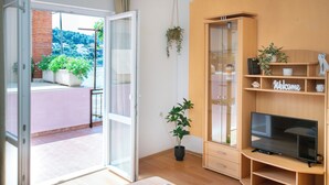 A modern living room with a TV, wooden shelving, and a balcony with potted plants. - Apartment Nela (Smokvica)