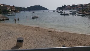 A harbor with boats, a sandy beach, and buildings in the background. - Apartment Nela (Smokvica)