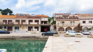 A coastal town with stone buildings, a clear waterfront, and parked cars. - Apartment Nela (Smokvica)