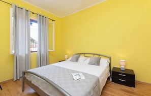 A room with a bed, a nightstand, and a window with curtains. - Apartment Nela (Smokvica)