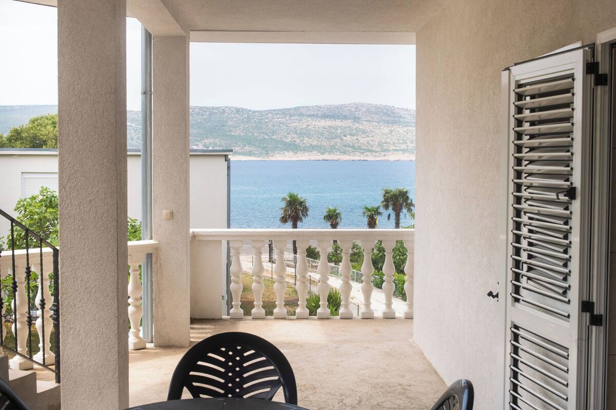 A balcony with a view of the sea and mountains.