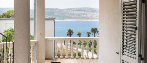 A balcony with a view of the sea and mountains.