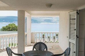 A balcony with a table and chairs, overlooking a body of water and a distant coastline. - Apartments More Sunce (Starigrad)