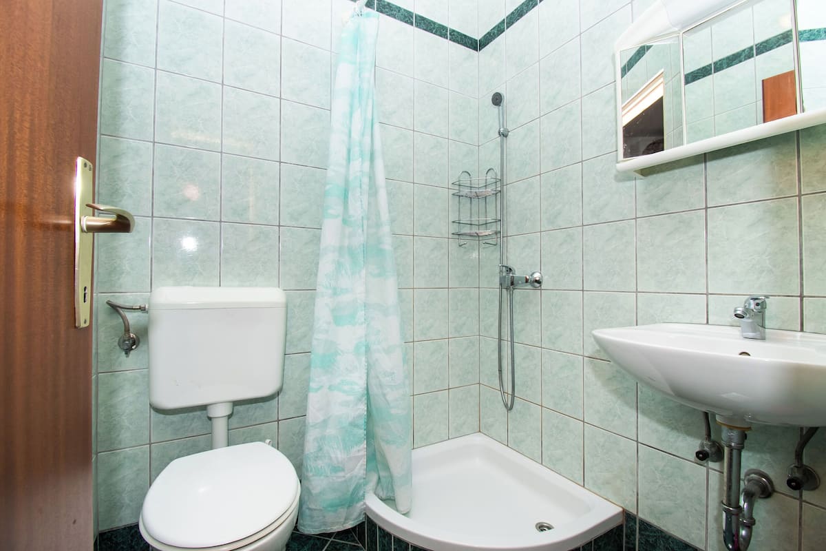 A bathroom with a toilet, shower, and sink.