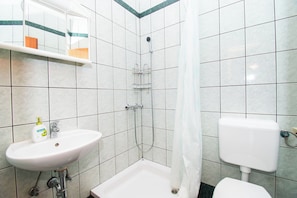 A bathroom with a sink, shower, toilet, and a mirror. - Apartments More Sunce (Starigrad)