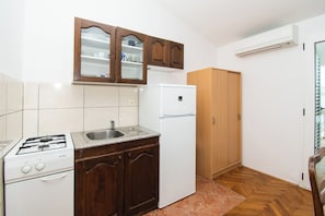 Eine Küche mit Gasherd, Spüle, einem weißen Kühlschrank, Holzschränken und einer Holztür.