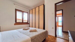A bedroom with a bed, a window, a wardrobe, and a door leading to a balcony. - Apartment Sandra (Novi Vinodolski)