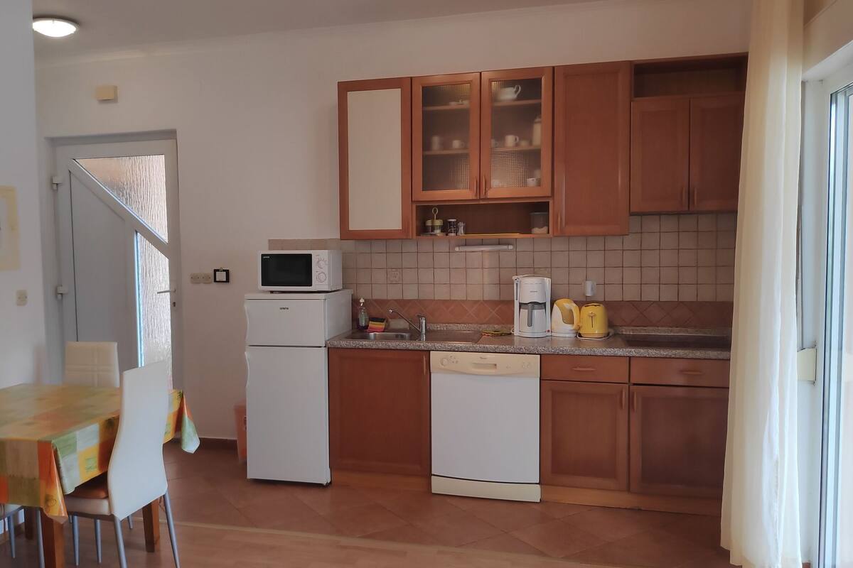 Une cuisine compacte avec des meubles en bois, un four à micro-ondes, une machine à café et un évier.