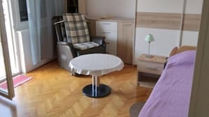 A bedroom with a bed, a chair, a small table, a wardrobe, and a ceiling light. - Apartments Sea Breeze (Umag)