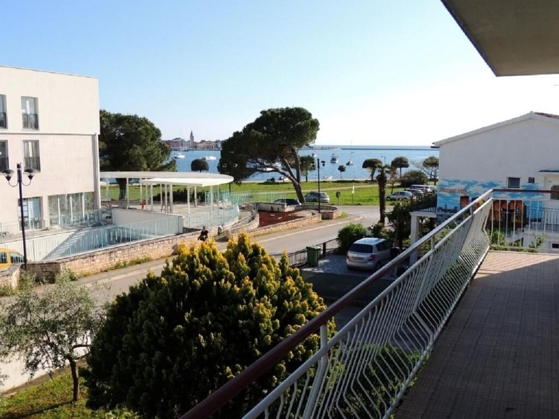 A modern building with a balcony, a covered outdoor area, and a view of a body of water.