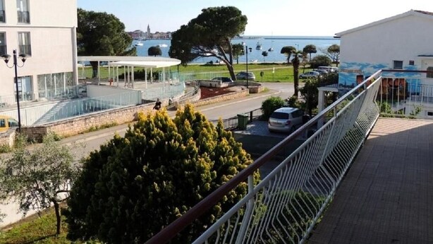 A modern building with a balcony, a covered outdoor area, and a view of a body of water. - Apartments Sea Breeze (Umag)