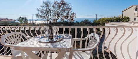 Un balcon avec une table et des chaises, offrant une vue panoramique sur un arbre et des bâtiments.