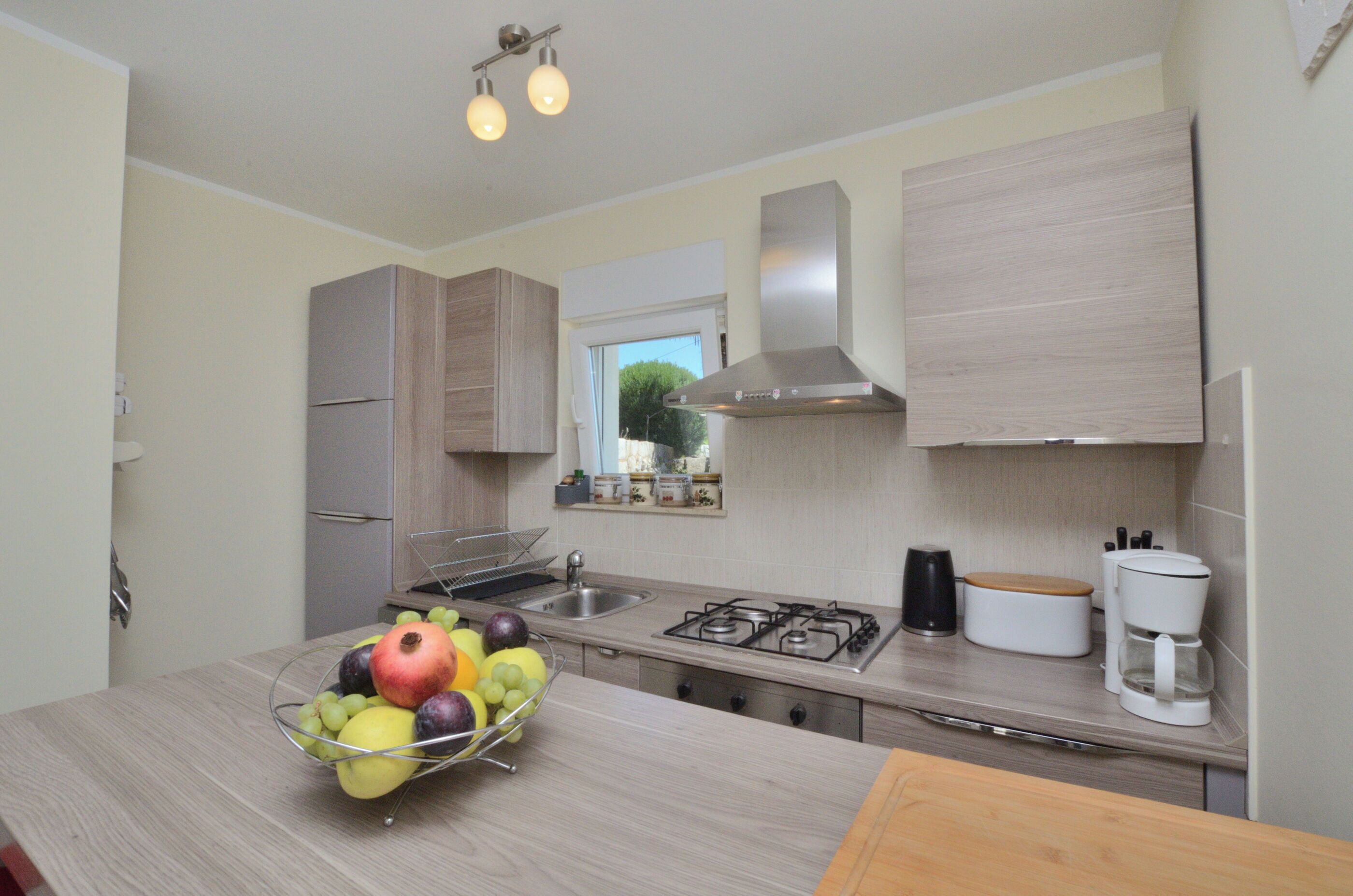 Una cucina moderna con piano cottura a gas, lavello in acciaio inox e mobili impiallacciati in legno.