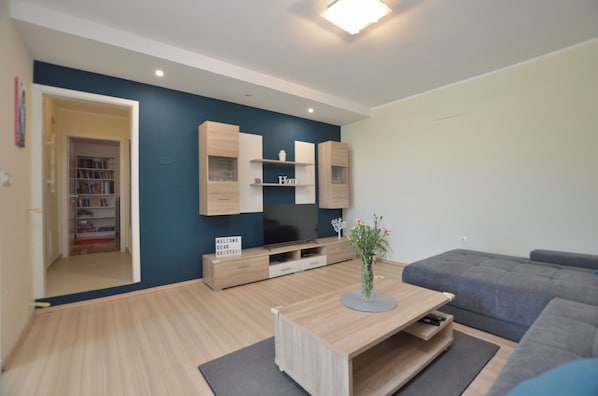 A modern living room with a flat-screen TV, wooden cabinets, a grey sofa, and a coffee table. - Apartment Hill (Moscenicka Draga)