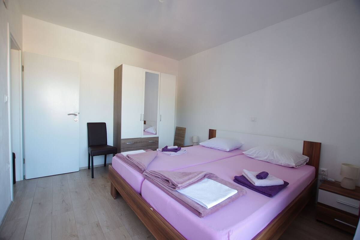 Ein Schlafzimmer mit Bett, Sessel, Kommode und Spiegel.