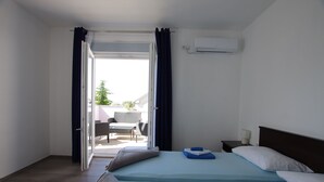 Habitación de hotel con cama, mesita de noche, unidad de aire acondicionado y vista al área de estar exterior.