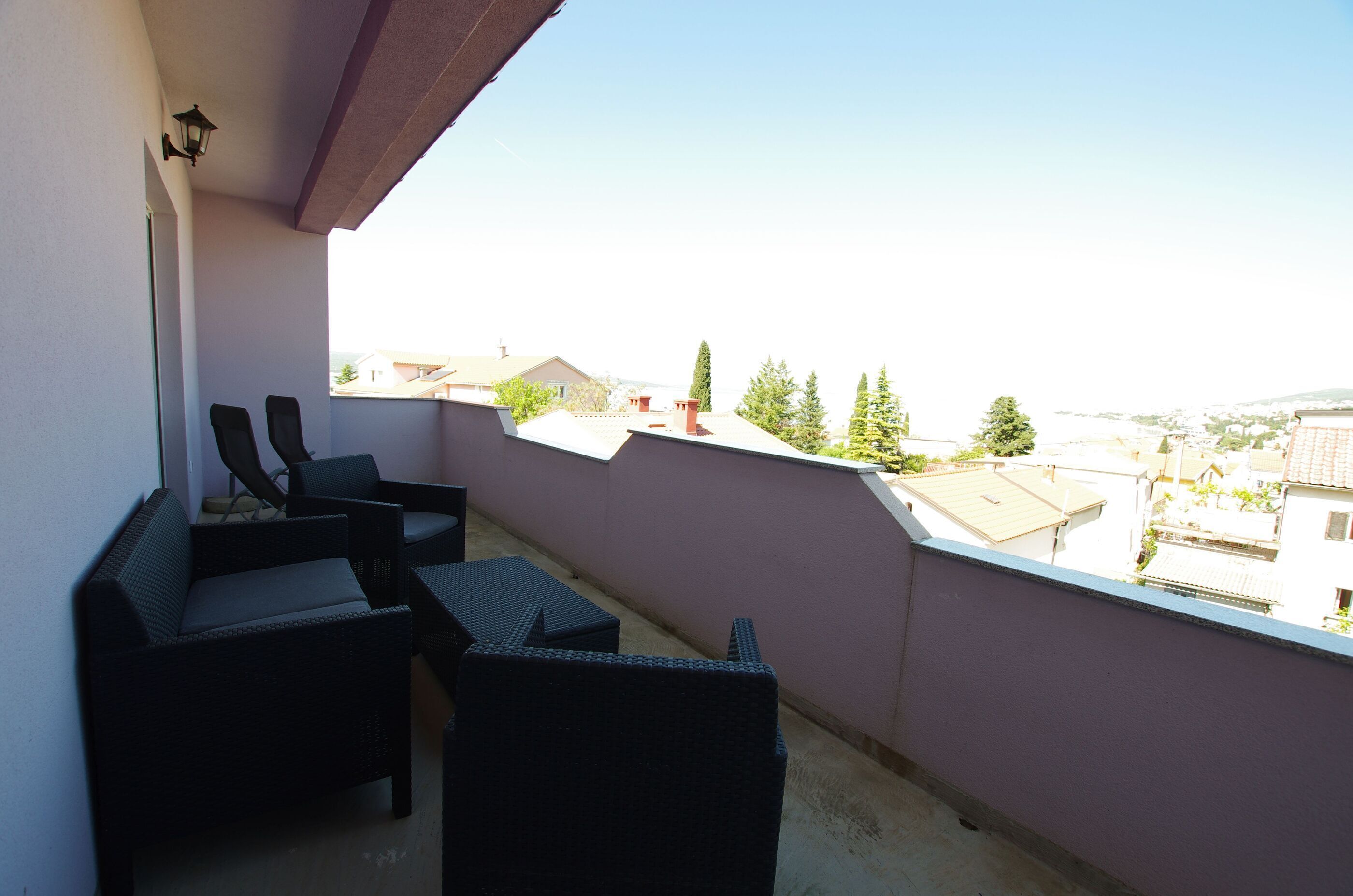 A balcony with wicker furniture and a view of the cityscape.