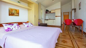 A hotel room with a bed, a desk, and two red chairs. - Apartments Dream View (Brela)