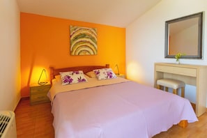 A bedroom with a bed, a nightstand, a dresser, a mirror, and a wall painting. - Apartments Dream View (Brela)