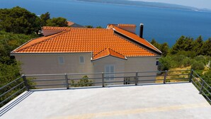 A building with a tiled roof overlooking a body of water. - Apartments Dream View (Brela)