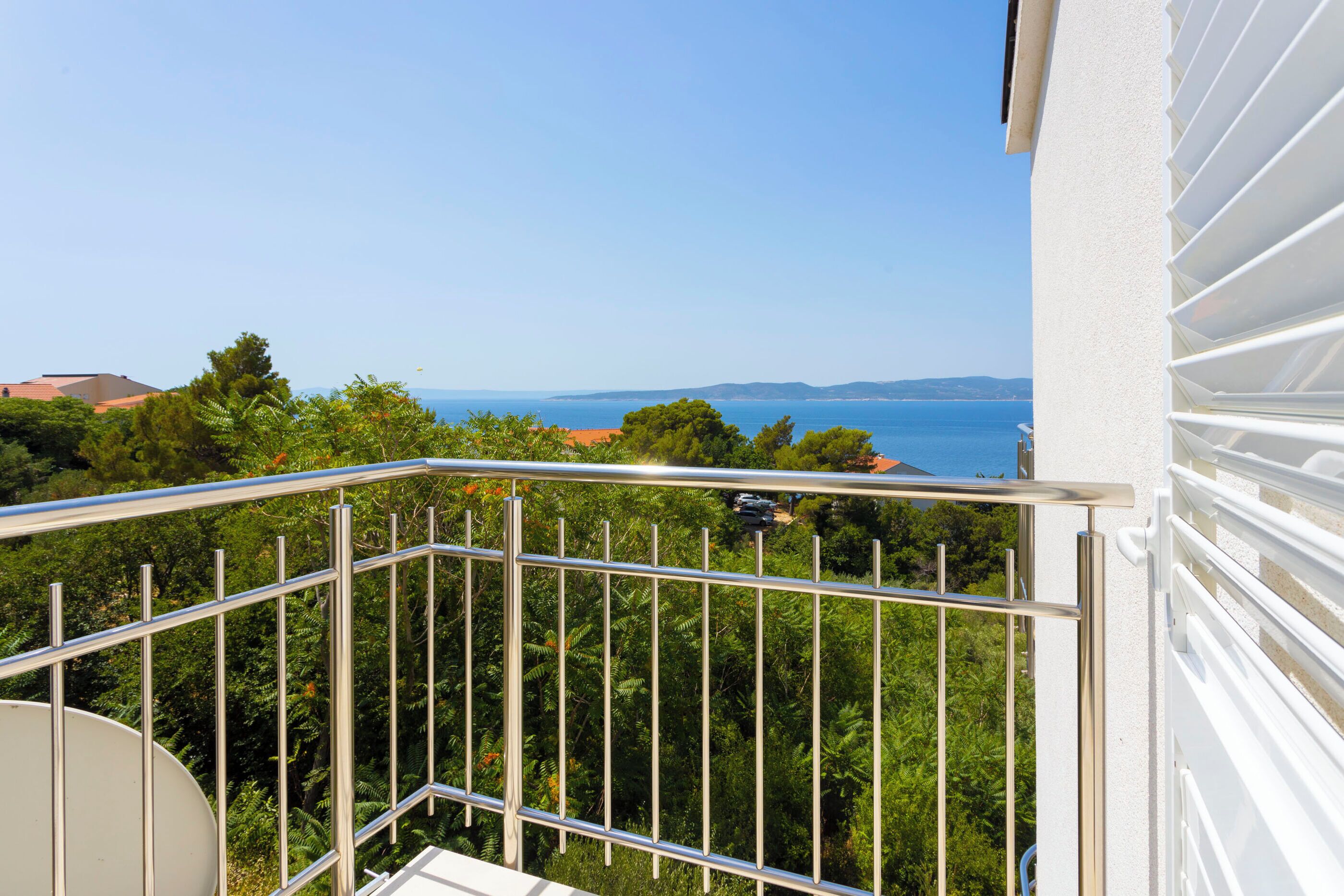 A balcony with a metal railing overlooking a sea view.