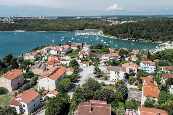 Eine Küstenstadt mit Wohnhäusern, einem Jachthafen mit Booten und freiem Blick auf das Meer.