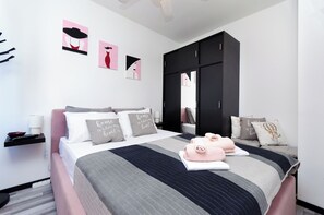 A modern bedroom with a bed, pillows, a wardrobe, and artwork on the wall. - Apartment Mare (Vrsar)
