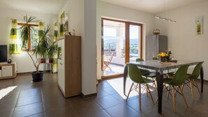 Een moderne keuken met een eethoek, een grote potplant en uitzicht op het omliggende landschap.