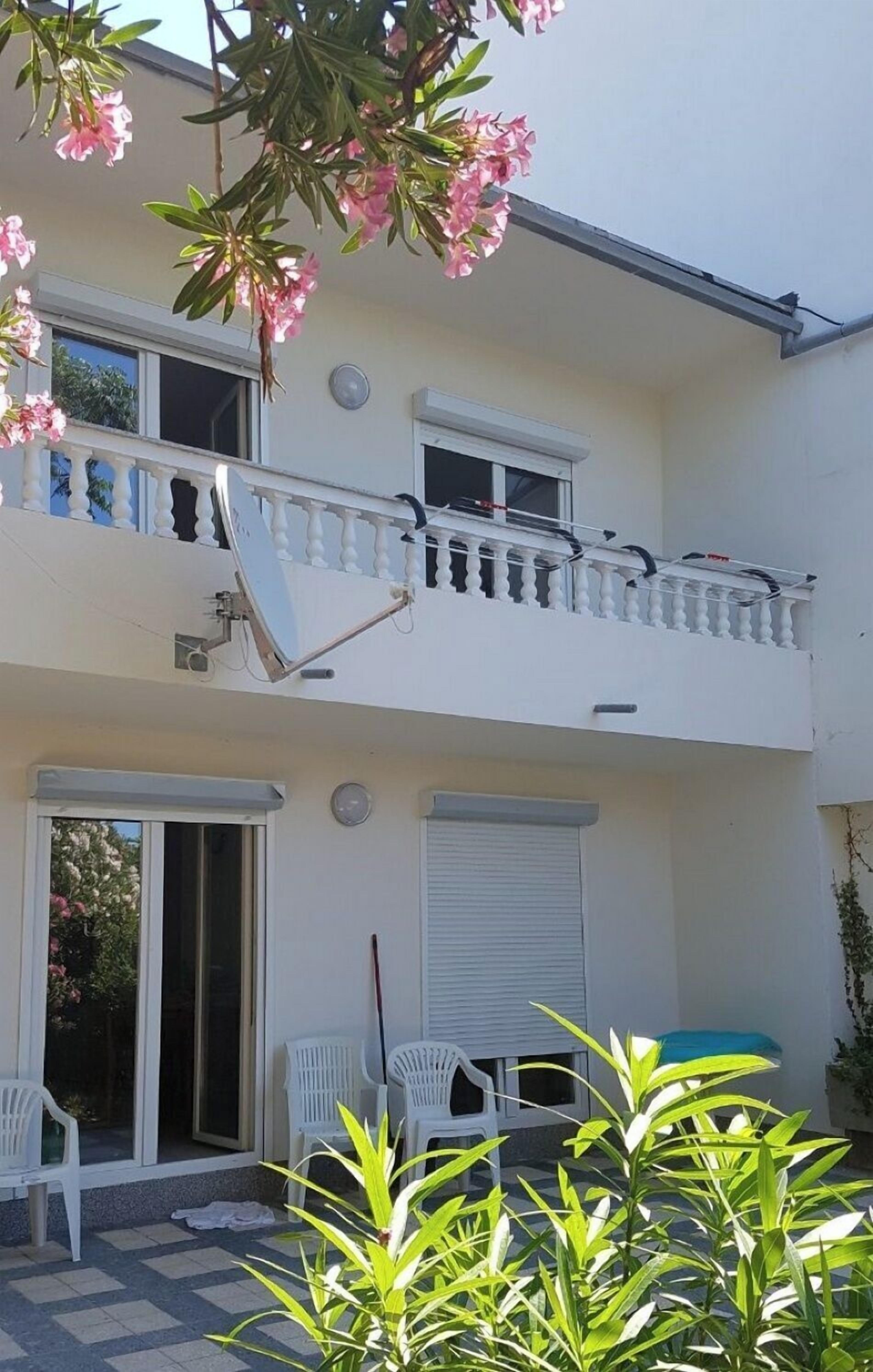A two-story building with a balcony, a satellite dish, and a sliding door.